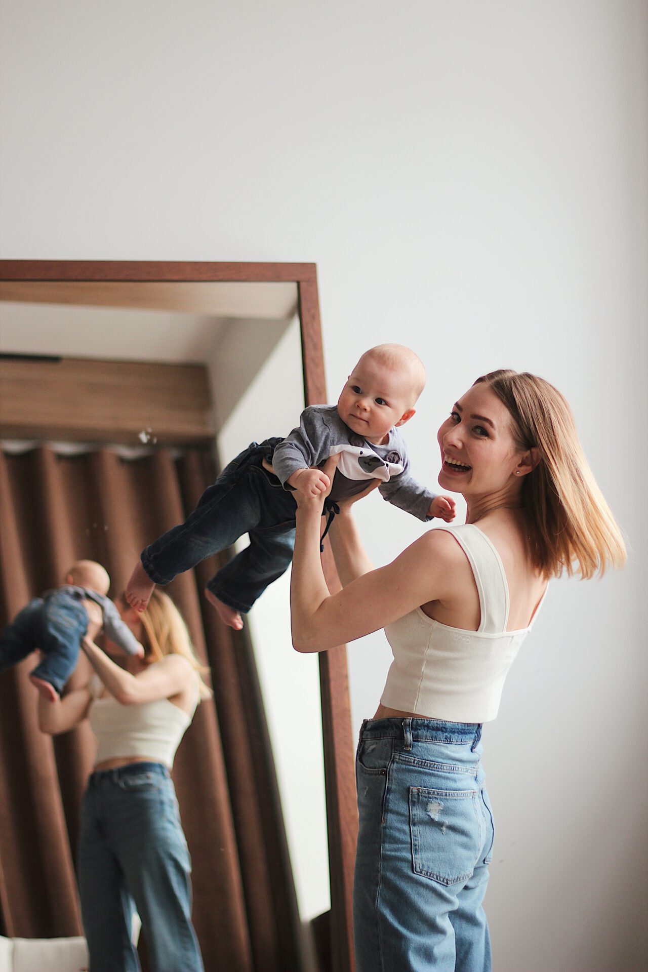 mom throwing baby in air in basement mirror