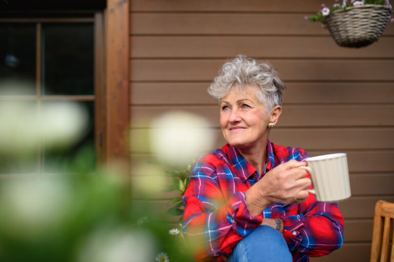 Senior Woman With Coffee Sitting On Terrace In Summer, Resting.