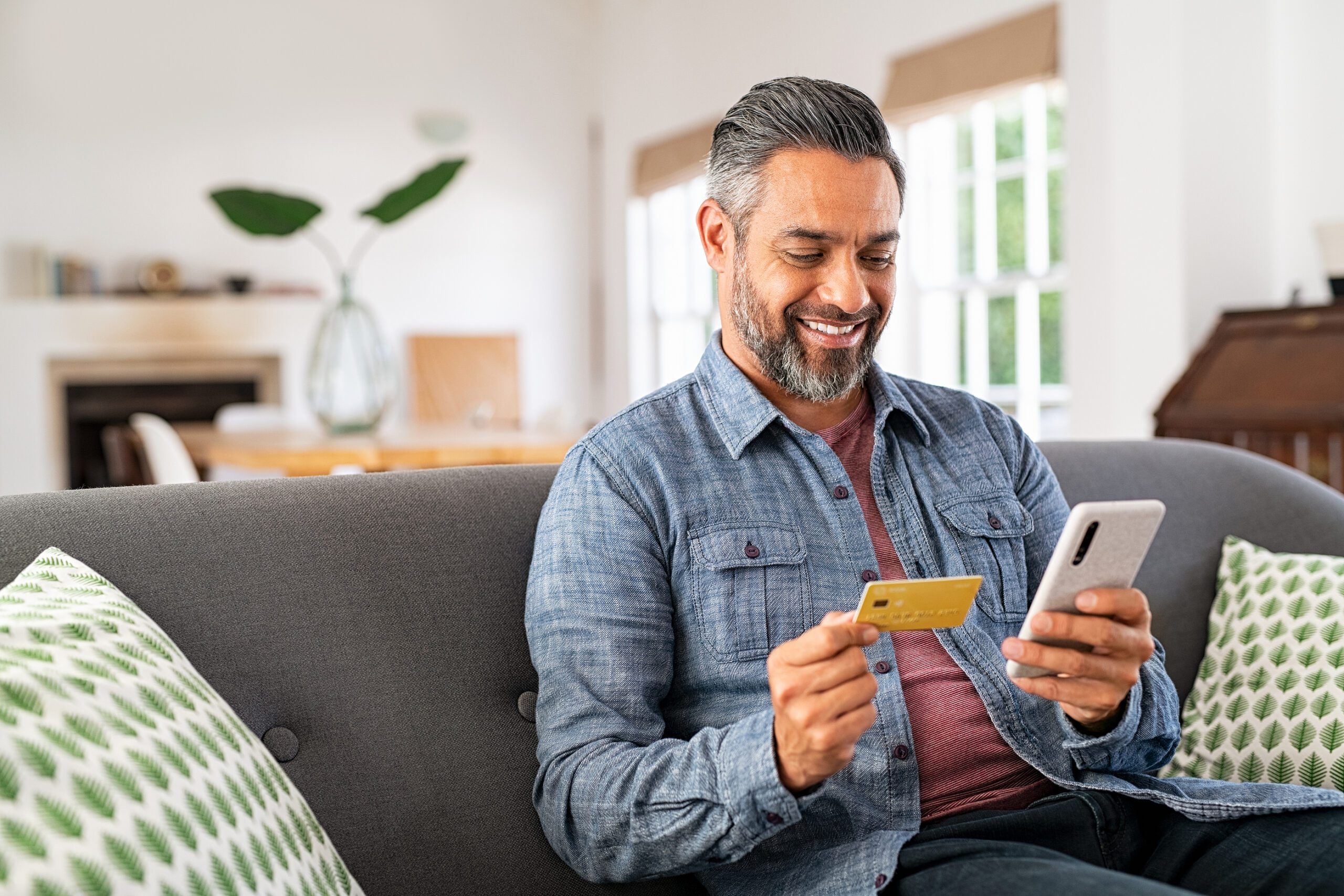 middle eastern man sitting on couch mobile banking